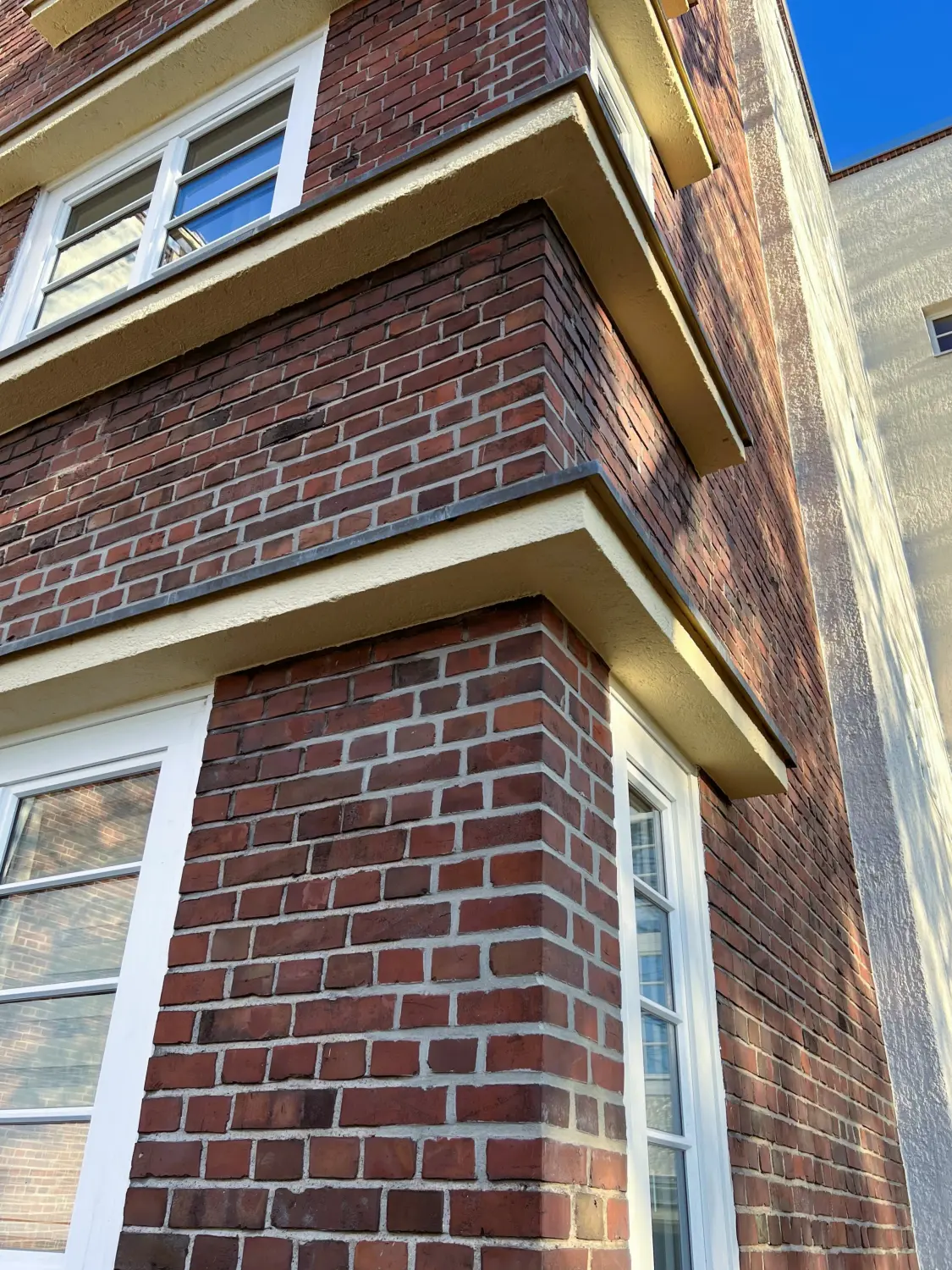 Fierle Baubetreuung - ein Wohngebäude aus roten Ziegeln mit Bauhaus-Architektur, mit vertikalen weißen Fenster