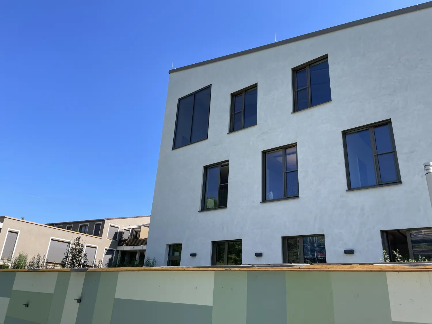 Fierle Baubetreuung – Ein modernes, mehrstöckiges Gebäude mit Flachdach und weißer Fassade