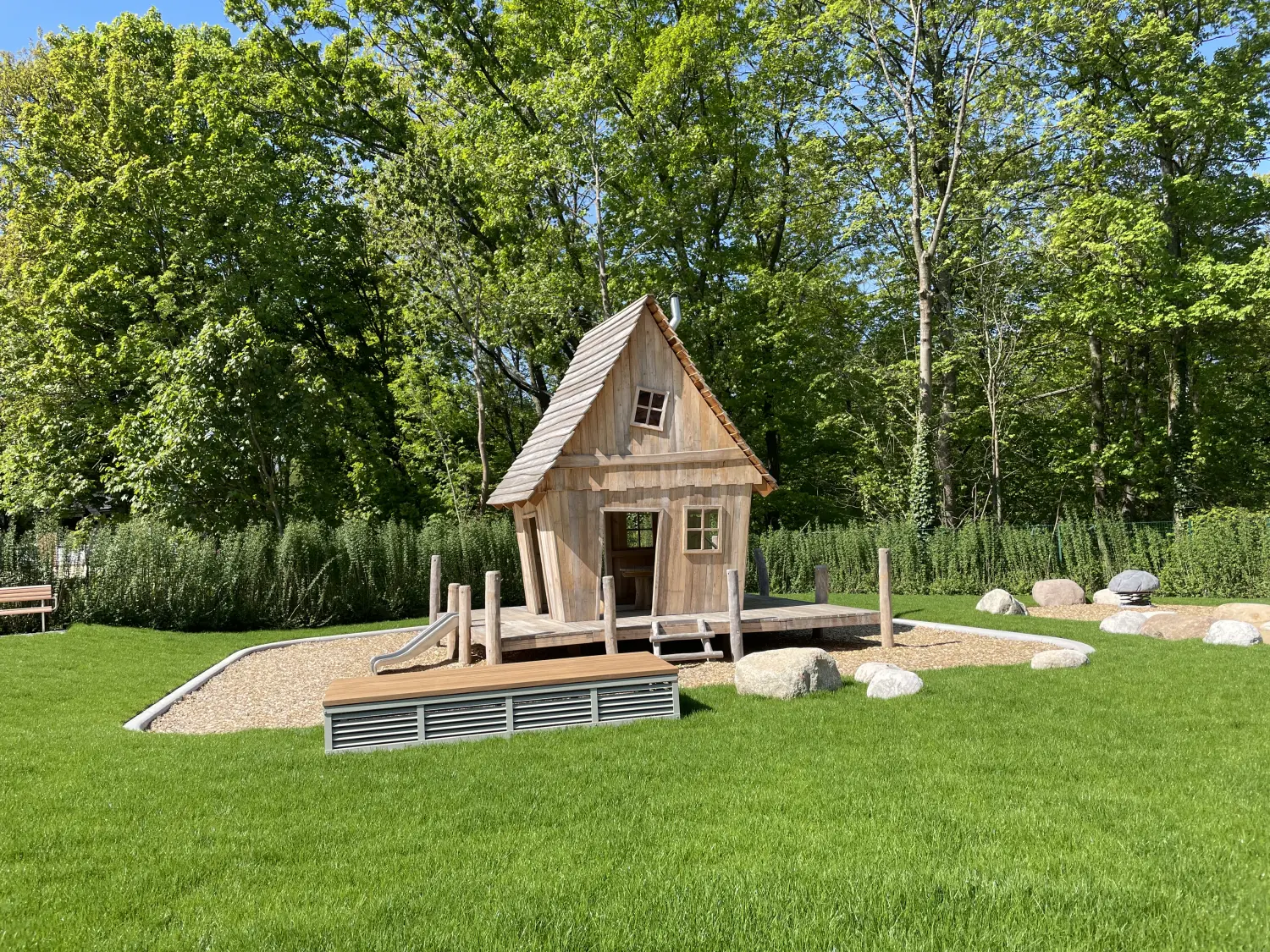 Fierle Baubetreuung – ein kleines Holzspielhaus auf einer Rasenfläche im Freien
